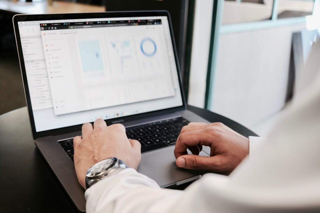 Close-up of hands typing on a laptop keyboard with data charts on screen